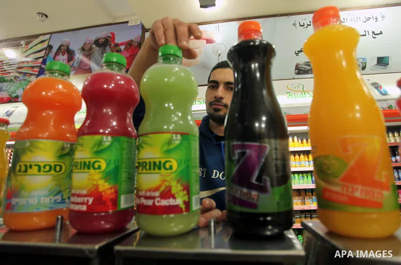 A Palestinian man sorts bottles of Israeli-product juice, at a mall in Gaza city on January 28, 2015. Gaza's Ministry of Economy said Sunday that it would allow soft drinks, clothes, coffee, and other Israeli products in...