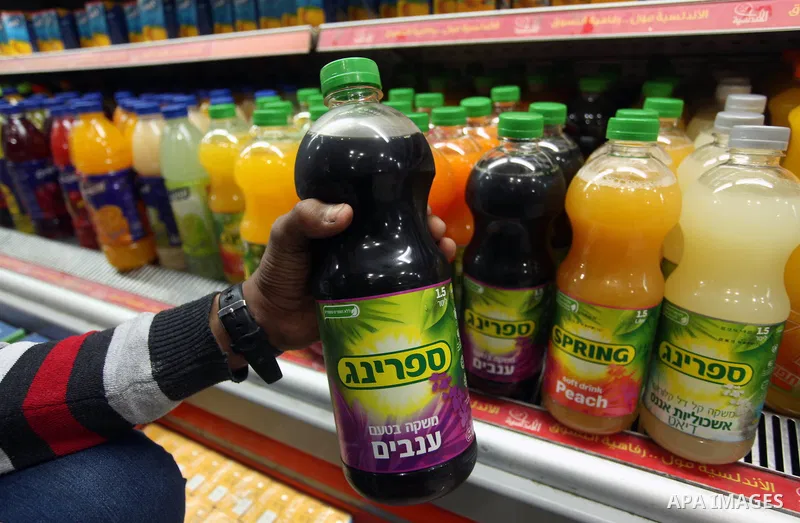 A Palestinian man displays a bottle of Israeli-product juice, at a mall in Gaza city on January 28, 2015. Gaza's Ministry of Economy said Sunday that it would allow soft drinks, clothes, coffee, and other Israeli product...