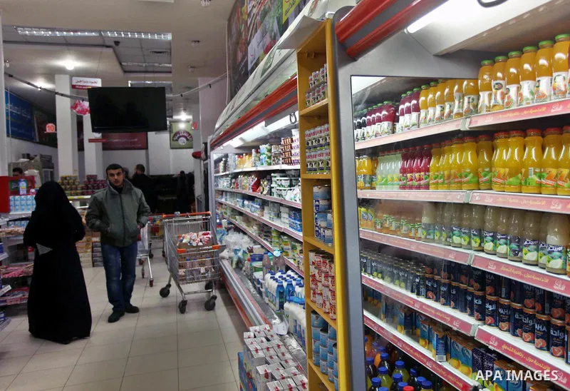 Palestinians look at bottles of Israeli-product juice, as they shop at a mall in Gaza city on January 28, 2015. Gaza's Ministry of Economy said Sunday that it would allow soft drinks, clothes, coffee, and other Israeli p...