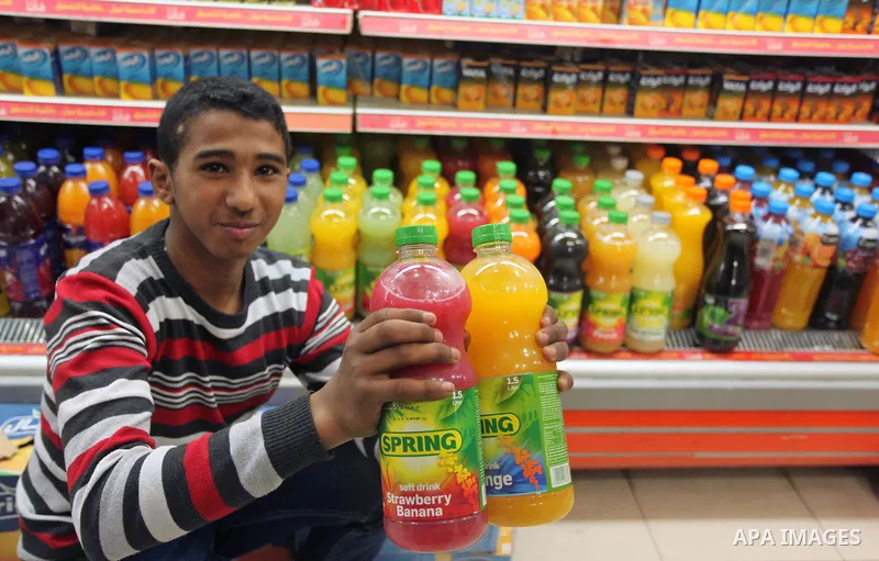 A Palestinian youth displays bottles of Israeli-product juice, at a mall in Gaza city on January 28, 2015. Gaza's Ministry of Economy said Sunday that it would allow soft drinks, clothes, coffee, and other Israeli produc...