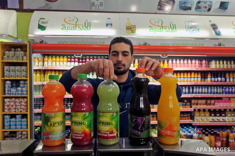 A Palestinian man sorts bottles of Israeli-product juice, at a mall in Gaza city on January 28, 2015. Gaza's Ministry of Economy said Sunday that it would allow soft drinks, clothes, coffee, and other Israeli products in...