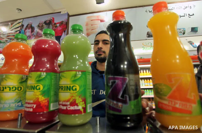 A Palestinian man sorts bottles of Israeli-product juice, at a mall in Gaza city on January 28, 2015. Gaza's Ministry of Economy said Sunday that it would allow soft drinks, clothes, coffee, and other Israeli products in...