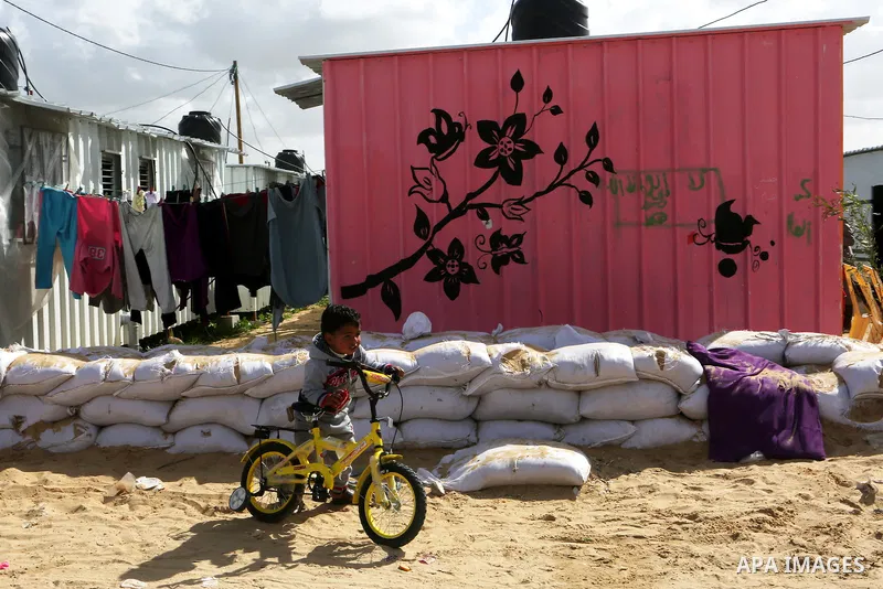 A Palestinian boy plays outside his family's container, which their house was destroyed by Israeli shelling during a 50-day conflict last summer, east if Khan Younis in the southern Gaza Strip, January 28, 2015. Dozens o...