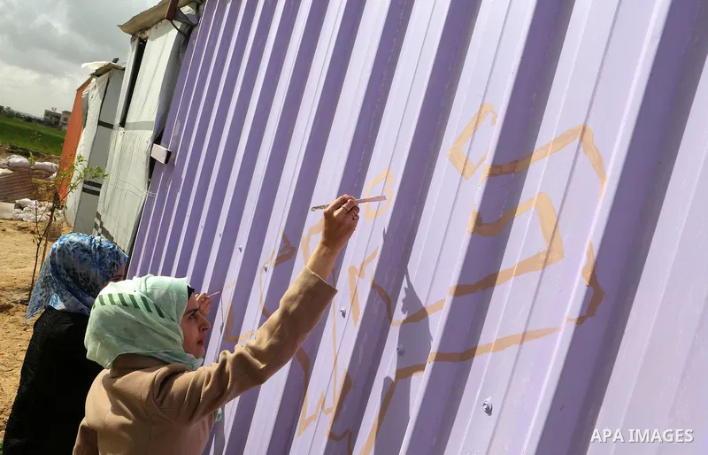Palestinian girls paint a container of a family, which their house was destroyed by Israeli shelling during a 50-day conflict last summer, east if Khan Younis in the southern Gaza Strip, January 28, 2015. Dozens of prote...