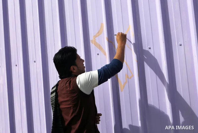 A Palestinian youth paints a container of a family, which their house was destroyed by Israeli shelling during a 50-day conflict last summer, east if Khan Younis in the southern Gaza Strip, January 28, 2015. Dozens of pr...