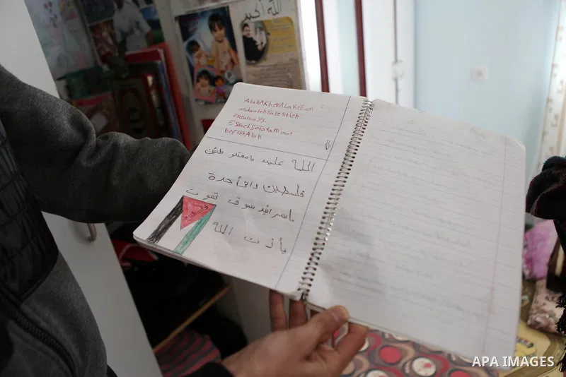 Palestinian Khawla Al-Khatib holds the notebook of her 14-year-old daughter Malak al-Khatib, detained in Israel, in the village of Beitin near the West Bank city of Ramallah, on January 29, 2015. The Palestinian suspect,...