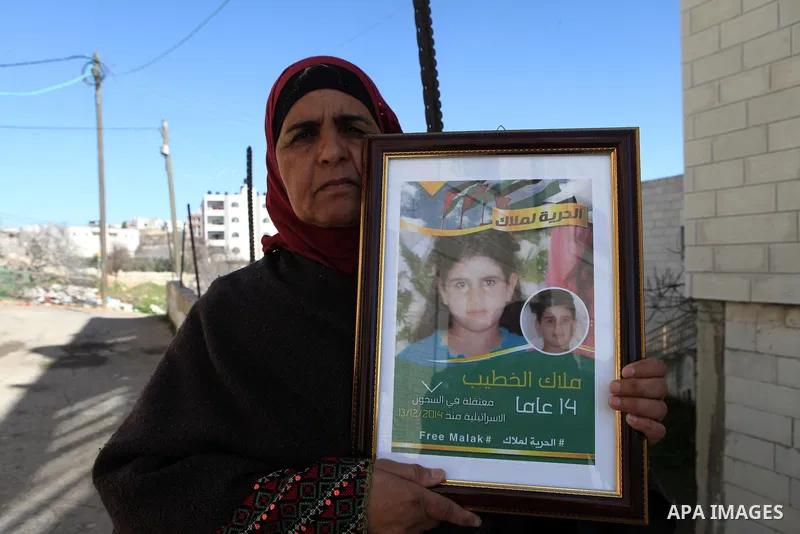 Palestinian Khawla Al-Khatib, holds a poster of her 14-year-old daughter Malak al-Khatib, detained in Israel, in the village of Beitin near the West Bank city of Ramallah, on January 29, 2014. The Palestinian suspect, ch...