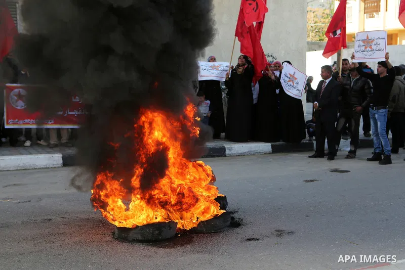Palestinian protesters burn tires during a protest organised by the Democratic Front for the Liberation of Palestine against United Nations, after the UN announced a lack of funds to rebuild the Palestinian territory, ou...