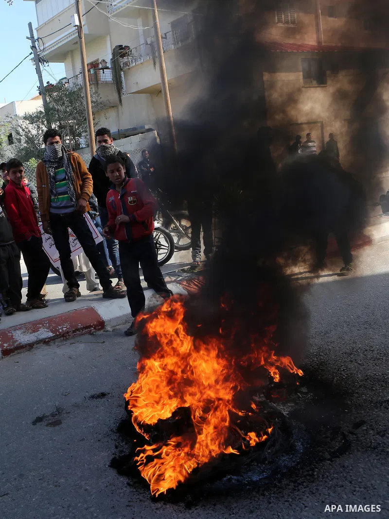 Palestinian protesters burn tires during a protest organised by the Democratic Front for the Liberation of Palestine against United Nations, after the UN announced a lack of funds to rebuild the Palestinian territory, ou...
