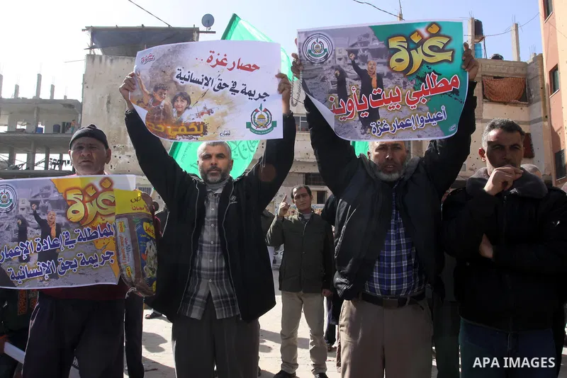 Palestinians hold placards during a protest against the United Nations decision to suspend payments for Palestinians, whose houses were damaged during a 50-day war last summer, in Beit Hanoun in the northern Gaza Strip J...