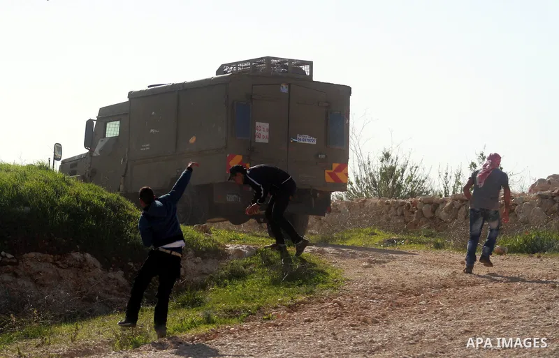 Palestinian protesters throw stones towards Israeli security forces during clashes following a protest against the arrest of 14-year-old girl Malak al-Khatib, in the West Bank village of Bilin west of Ramallah, on Januar...