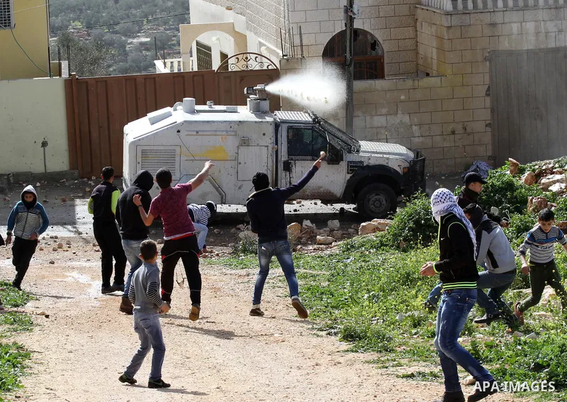Palestinian protesters throw stones at an Israeli military water canon during clashes following a demonstration against the expropriation of Palestinian land by Israel in the village of Kfar Qaddum, near Nablus in the oc...