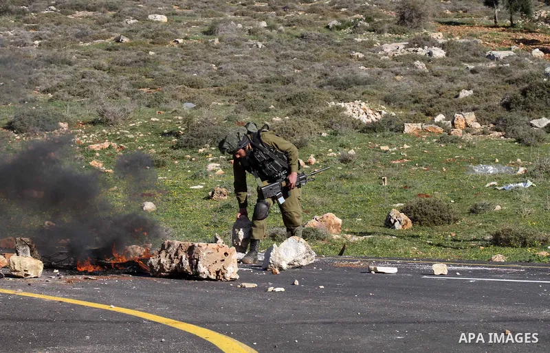 An Israeli solider carries a rock during clashes with Palestinian protesters in the village of Qusra, near Nablus in the occupied West Bank, on February 2, 2015. Israeli forces on Monday demolished two small farmhouses,...