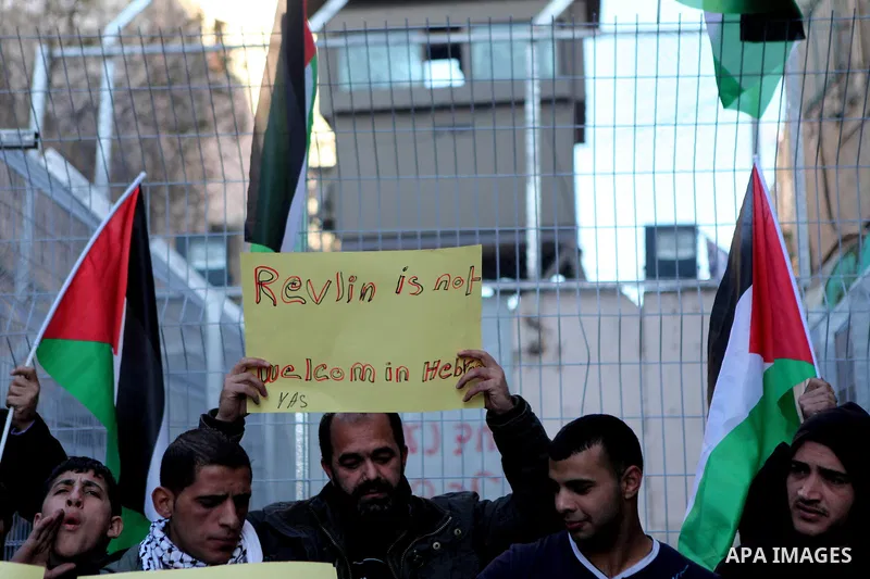 Palestinians hold banners and flags during a demonstration against the visit of Israeli President Reuven Rivlin to attend the dedication ceremony of the Hebron Heritage Museum , near an Israeli check point in the centre...