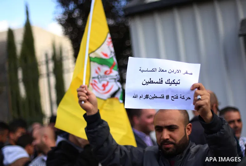 Palestinians hold banners during a protest to show solidarity with the Jordanian pilot Muath al-Kasaesbeh, who was died by the hardline group in front of the Jordanian Embassy in the West Bank city of Ramallah, on Februa...