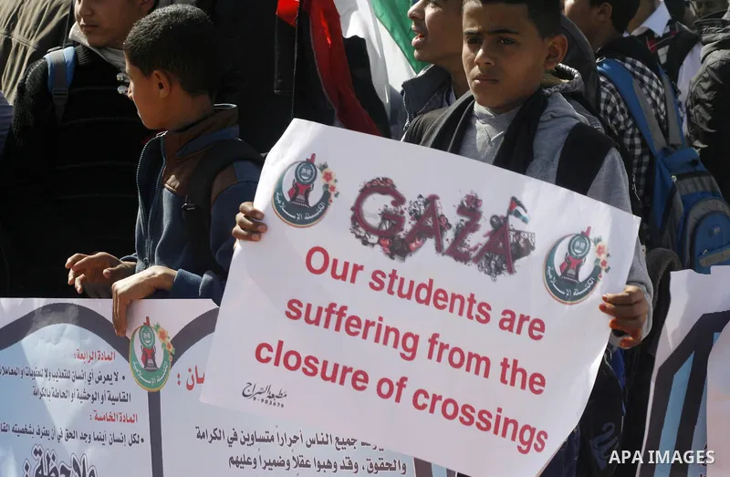 Palestinian students hold banners during a protest outside the Rafah crossing border, demanding the Egyptian authorities for the opening of the crossing, in Rafah in the southern Gaza Strip, February 4, 2015. Photo by Ab...