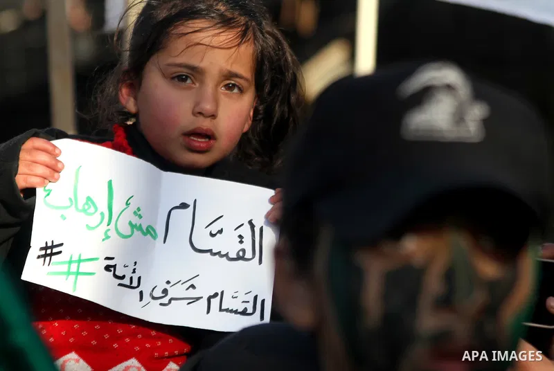 A Palestinian girl holds a banner during a rally to condemn the decision of an Egyptian court to ban the armed wing of Palestinian Islamist movement, near the Rafah border between southern Gaza Strip and Egypt on Februar...