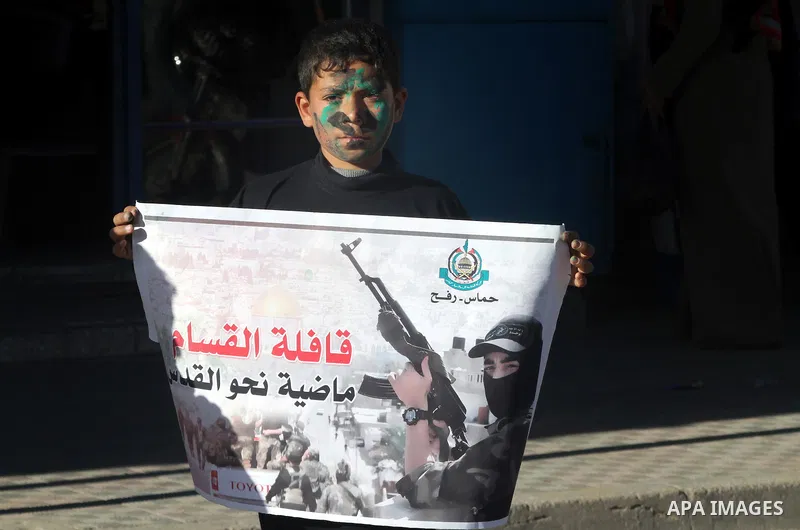 A Palestinian youth holds a banner during a rally to condemn the decision of an Egyptian court to ban the armed wing of Palestinian Islamist movement, near the Rafah border between southern Gaza Strip and Egypt on Februa...