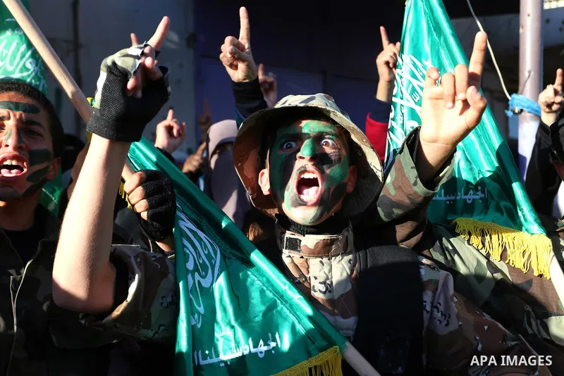 Palestinian youths hold Hamas movement flags and shout slogans during a rally to condemn the decision of an Egyptian court to ban the armed wing of Palestinian Islamist movement, near the Rafah border between southern Ga...