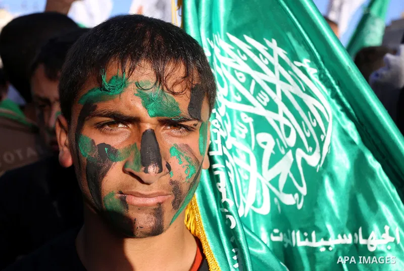 A Palestinian youth holds Hamas movement flag during a rally to condemn the decision of an Egyptian court to ban the armed wing of Palestinian Islamist movement, near the Rafah border between southern Gaza Strip and Egyp...
