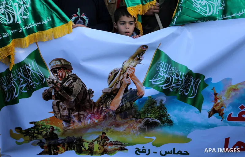 A Palestinian boy looks on behind a banner during a rally to condemn the decision of an Egyptian court to ban the armed wing of Palestinian Islamist movement, near the Rafah border between southern Gaza Strip and Egypt o...