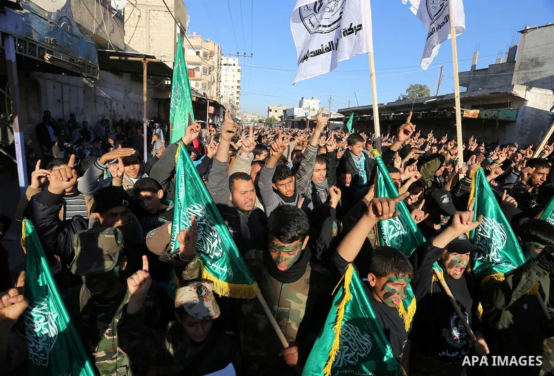 Palestinian youths hold Hamas movement flags during a rally to condemn the decision of an Egyptian court to ban the armed wing of Palestinian Islamist movement, near the Rafah border between southern Gaza Strip and Egypt...