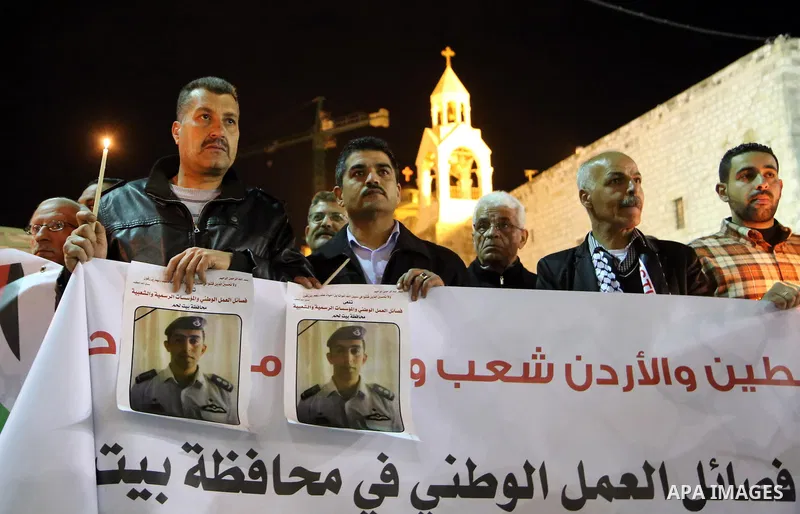 Palestinians hold candles and portraits of slain Jordanian pilot, Lt. Muath al-Kasasbeh, killed by the Islamic State group, during a candle light vigil outside the Nativity Church in the West Bank city of Bethlehem, Febr...
