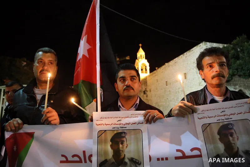 Palestinians hold candles and portraits of slain Jordanian pilot, Lt. Muath al-Kasasbeh, killed by the Islamic State group, during a candle light vigil outside the Nativity Church in the West Bank city of Bethlehem, Febr...