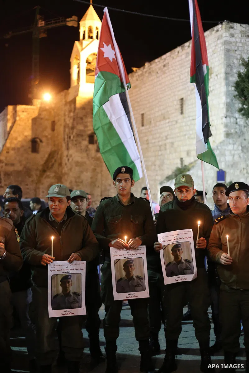 Palestinian security forces hold candles and portraits of slain Jordanian pilot, Lt. Muath al-Kasasbeh, killed by the Islamic State group, during a candle light vigil outside the Nativity Church in the West Bank city of...