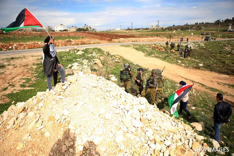 A Palestinian woman waves a Palestinian flag in front of Israeli troops during clashes at a weekly protest against Jewish settlements, in the West Bank village of Nabi Saleh, near Ramallah February 6,2015. Photo by Shadi...