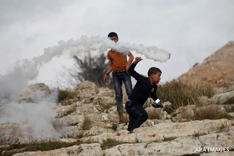 A Palestinian youth runs for cover from tear gas during clashes with Israeli troops at a weekly protest against Jewish settlements, in the West Bank village of Nabi Saleh, near Ramallah February 6,2015. Photo by Shadi Ha...
