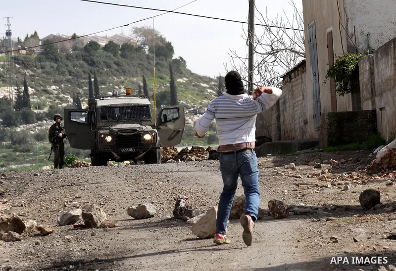 A Palestinian youth throws stones towards Israeli security forces during clashes following a demonstration against the expropriation of Palestinian land by Israel in the village of Kfar Qaddum, near Nablus in the occupie...