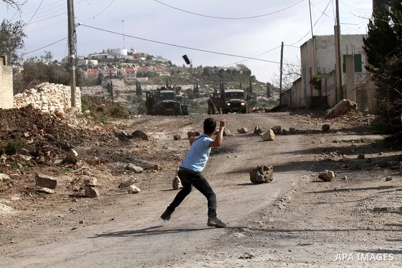 A Palestinian youth uses a sling shot to hurl a stone at Israeli security forces during clashes following a demonstration against the expropriation of Palestinian land by Israel in the village of Kfar Qaddum, near Nablus...