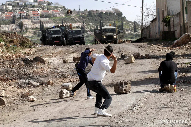 Palestinian youths throw stones towards Israeli security forces during clashes following a demonstration against the expropriation of Palestinian land by Israel in the village of Kfar Qaddum, near Nablus in the occupied...