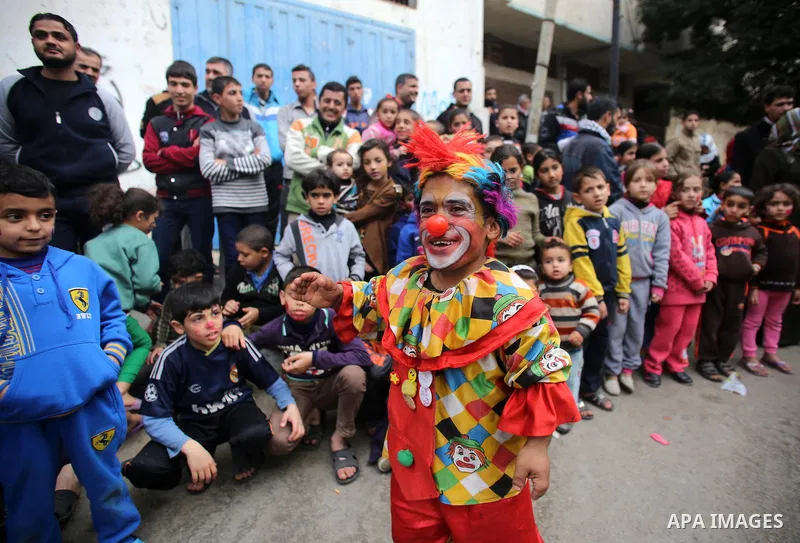A clown performs in front of Palestinian children during a street game organised by volunteers of the Friday of Joy Initiative, in al-Shati refugee camp, in Gaza city, February 6, 2015. Ten Palestinian volunteers organis...