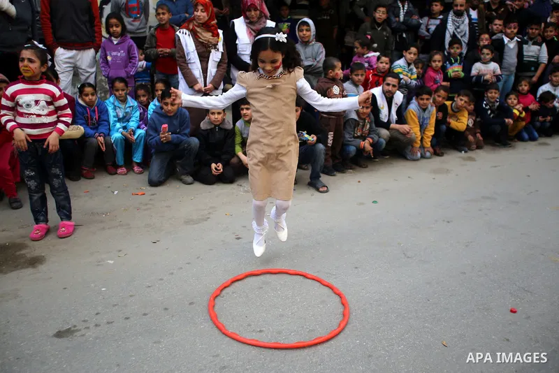 A Palestinian girl plays during a street game organised by volunteers of the Friday of Joy Initiative, in al-Shati refugee camp, in Gaza city, February 6, 2015. Ten Palestinian volunteers organise street games, painting...