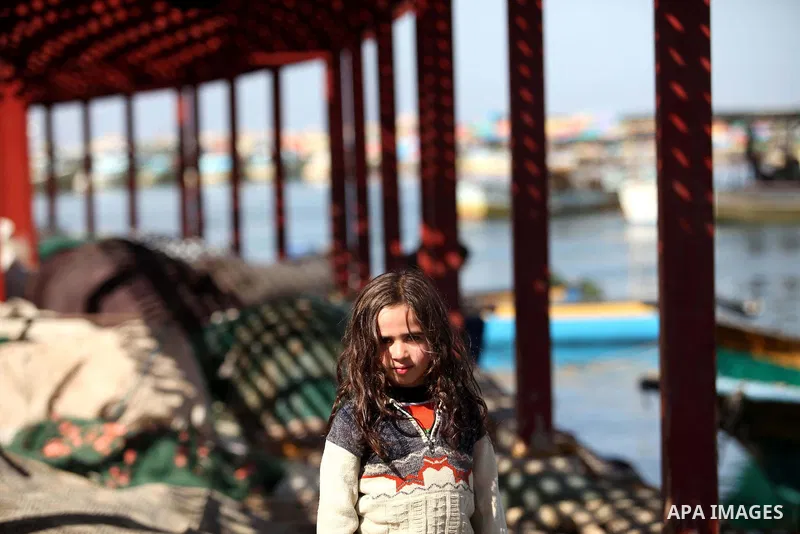 A Palestinian girl poses for a picture as she plays on a fishing boat at the Gaza seaport, on February 7, 2015. The Israeli military boats on Friday morning opened fire on the Palestinian fishermen's boats near Al-Sudane...