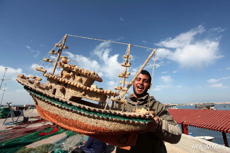 A Palestinian man holds a fishing boat model at the Gaza seaport, on February 7, 2015. The Israeli military boats on Friday morning opened fire on the Palestinian fishermen's boats near Al-Sudaneyya shore northwest of Ga...