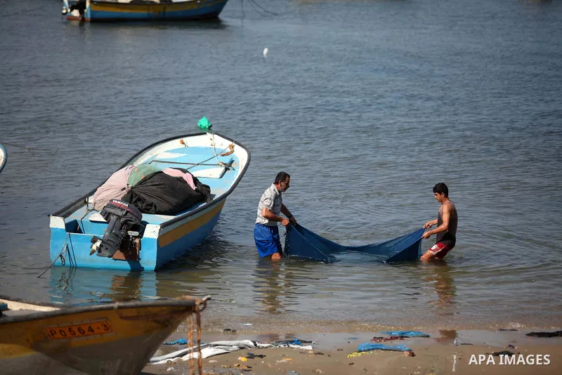Palestinian fishermen work near their boats at the Gaza seaport, on February 7, 2015. The Israeli military boats on Friday morning opened fire on the Palestinian fishermen's boats near Al-Sudaneyya shore northwest of Gaz...