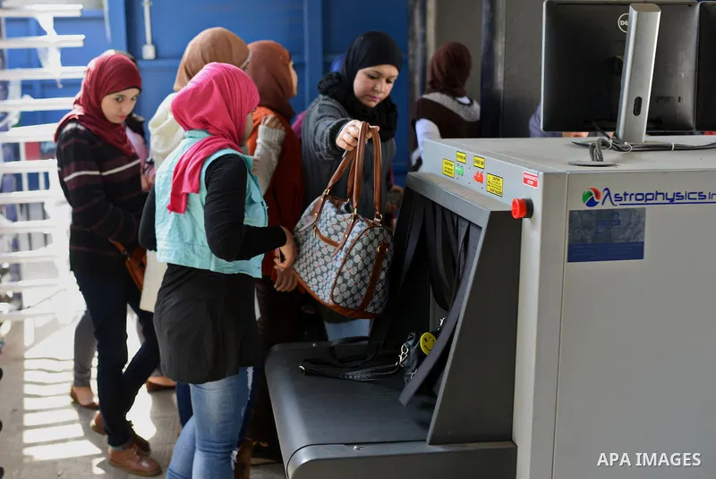 Egyptian students push their bags at an X-ray machine for screening at the entrance of Cairo University during the first day of the second term of the 2014-15 academic year on February 7, 2015. Due to the escalation of s...