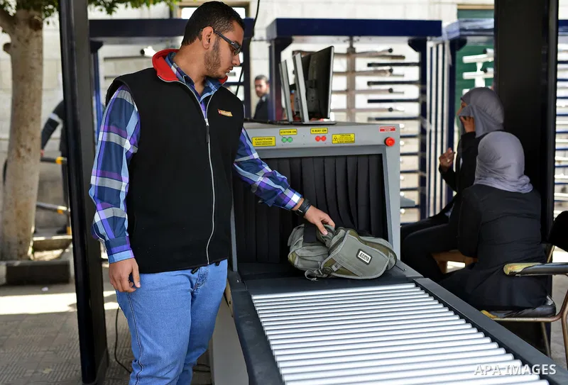 An Egyptian student holds his bag at an X-ray machine after screening at the entrance of Cairo University during the first day of the second term of the 2014-15 academic year on February 7, 2015. Due to the escalation of...