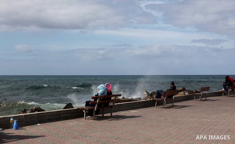Palestinians sit in front of the beach at the Gaza seaport, on February 8, 2015. The governmental Committee to Break the Siege on Gaza declared last month the beginning of the rehabilitation of a waterway that would link...