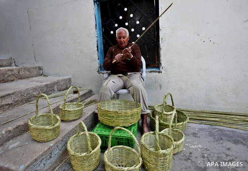 Palestinian Abu Ali Salhat, 80, works on a traditional straw basket, at his house near the West Bank city of Nablus, February 8, 2015. Photo by Nedal Eshtayah