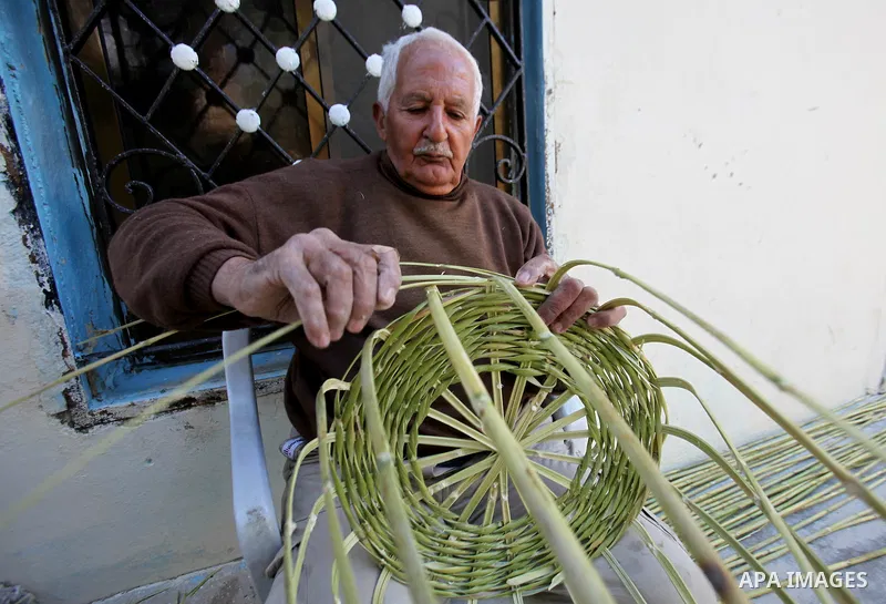 Palestinian Abu Ali Salhat, 80, works on a traditional straw basket, at his house near the West Bank city of Nablus, February 8, 2015. Photo by Nedal Eshtayah