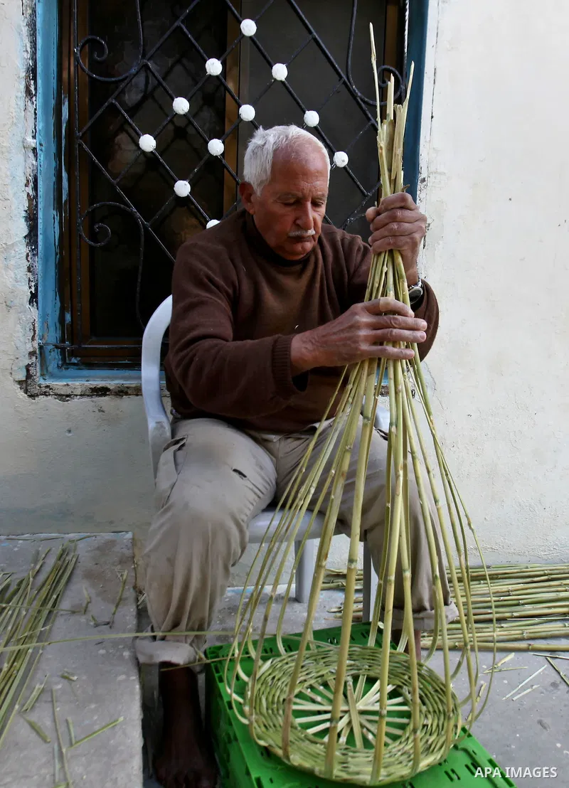 Palestinian Abu Ali Salhat, 80, works on a traditional straw basket, at his house near the West Bank city of Nablus, February 8, 2015. Photo by Nedal Eshtayah
