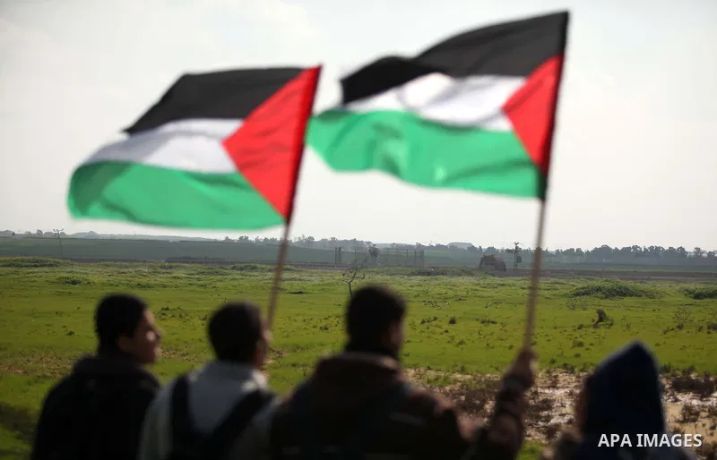 Palestinian protesters wave their national flags during a protest against the Israeli siege on Gaza strip near the Nahal Oz crossing east of Gaza City on February 09, 2015. Photo by Ashraf Amra