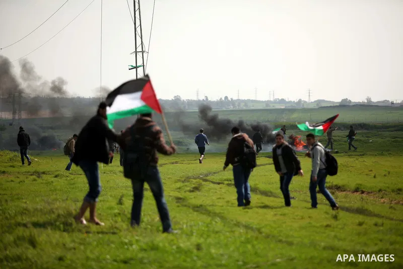 Palestinian protesters wave their national flags during a protest against the Israeli siege on Gaza strip near the Nahal Oz crossing east of Gaza City on February 09, 2015. Photo by Ashraf Amra