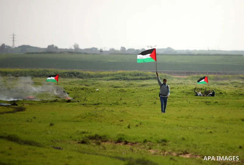 A Palestinian protestor waves his national flags during a protest against the Israeli siege on Gaza strip near the Nahal Oz crossing east of Gaza City on February 09, 2015. Photo by Ashraf Amra