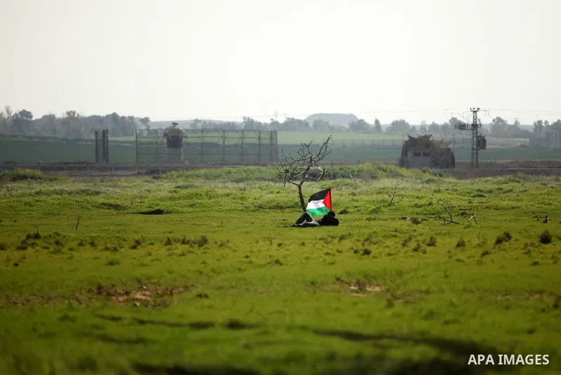 A Palestinian protestor waves his national flags during a protest against the Israeli siege on Gaza strip near the Nahal Oz crossing east of Gaza City on February 09, 2015. Photo by Ashraf Amra