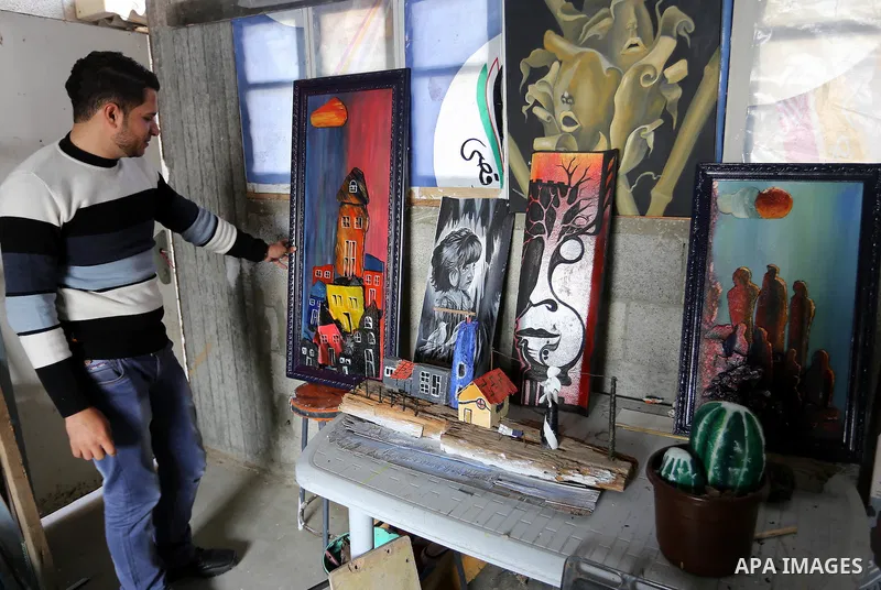 A Palestinian man displays a painting at an atelier in Rafah in the southern Gaza Strip, February 9, 2015. Three Palestinian artists use the remains of houses which were destroyed during the 51 day Israeli recent war on...